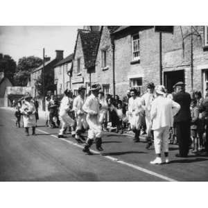 Villagers Watch a Morris Dancing Team Perform in the Middle of a Road 
