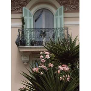 Wrought Iron Balcony and Shuttered Windows Above a Flowering Garden 